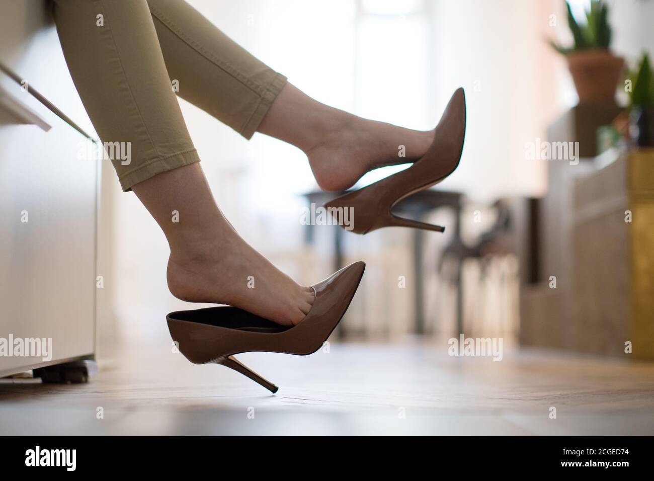 Mujer cansada está descansando quitándose sus zapatos marrones de tacón  alto después de trabajar o caminar, acostada en el sofá. Zapatos incómodos  Fotografía de stock - Alamy