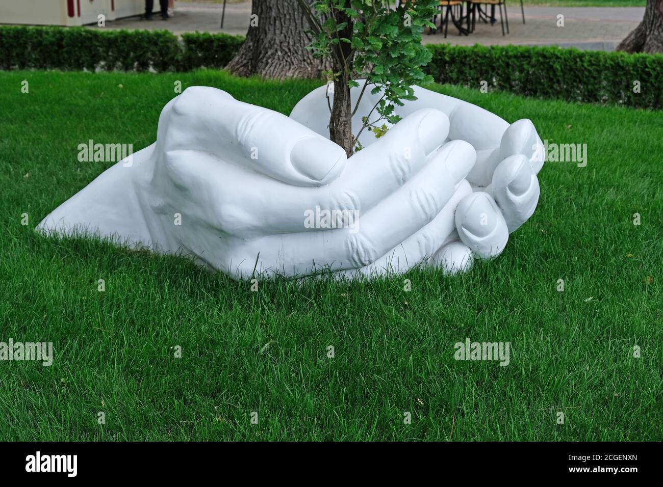 escultura de una mano hecha de yeso sobre un fondo de césped verde.  concepto salvo cuidar de la naturaleza. las manos humanas se reúnen cerca  de un gro Fotografía de stock 