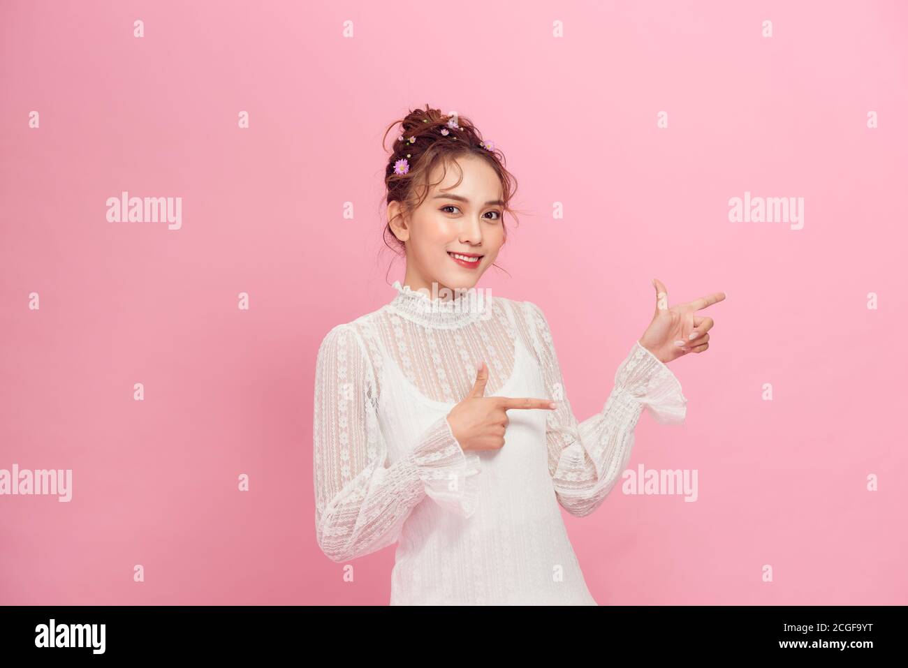 hermosa chica feliz señalando con los dedos en el espacio de copia aislado sobre rosa Foto de stock