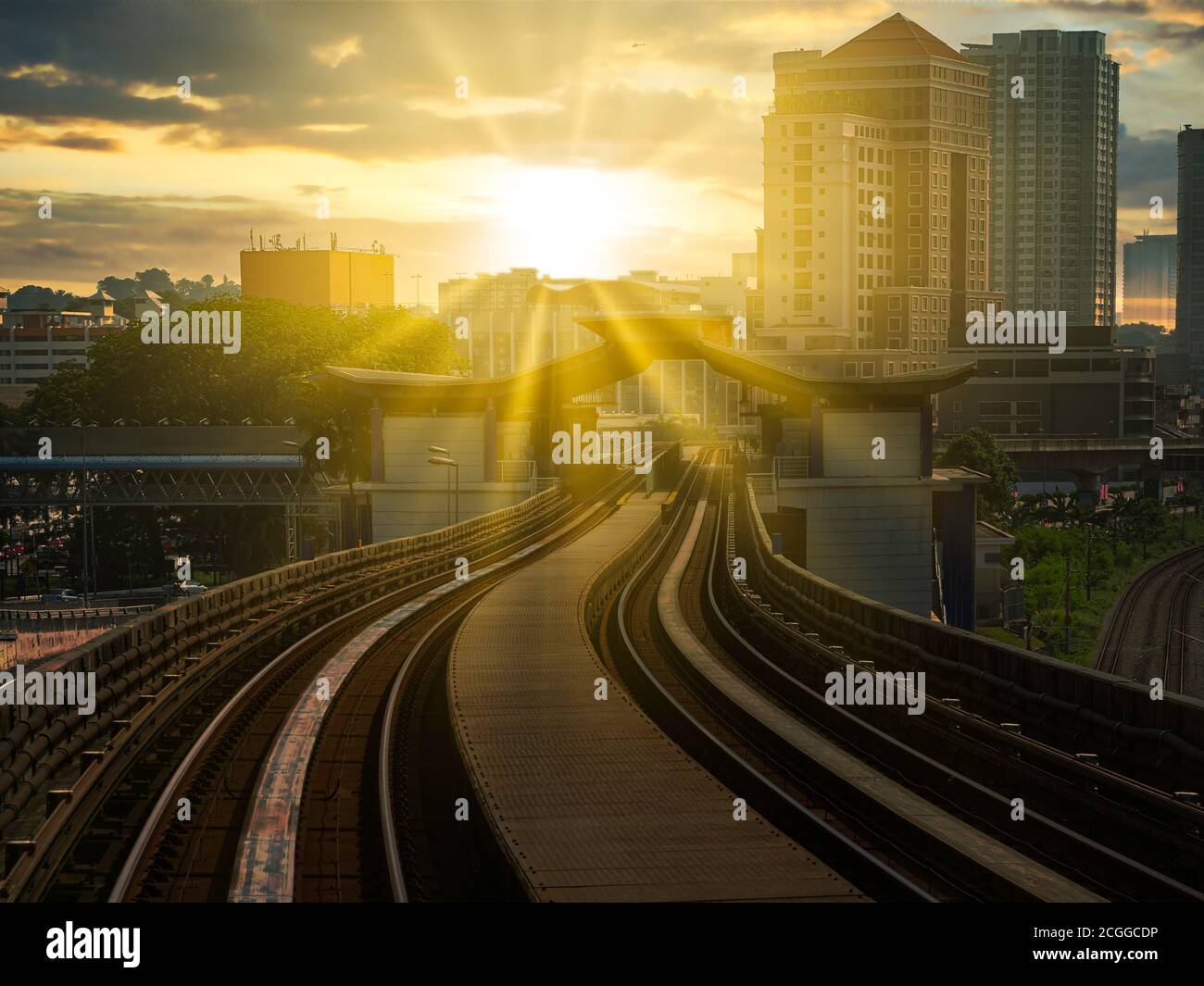 Ir a trabajar en tren bajo un brillante amanecer soleado con el paisaje urbano y la construcción en el horizonte Foto de stock