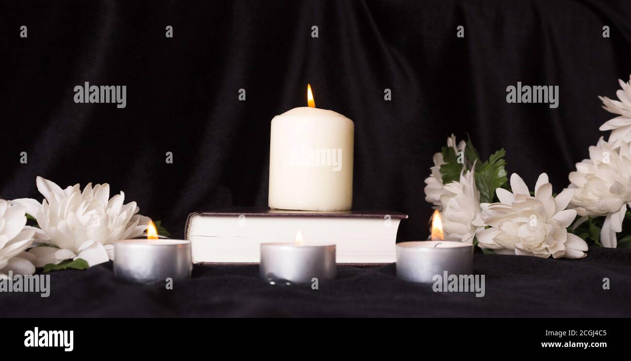 Tarjeta de condolencia. Una vela blanca con flores blancas y un libro. El  funeral, la tristeza Fotografía de stock - Alamy
