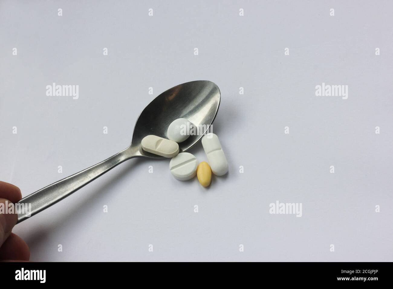 Tabletas en la cuchara. Administración de medicamentos. Tema: Interacción droga-droga. Foto de stock
