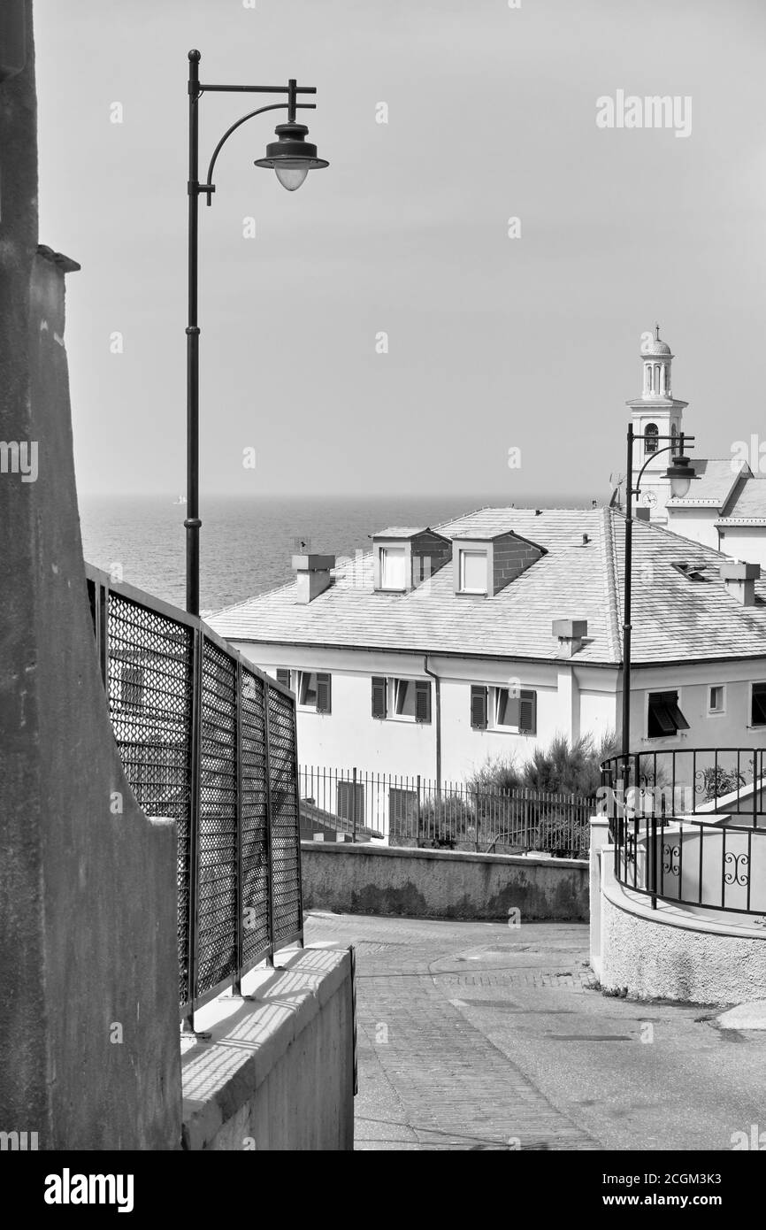 Calle cuesta abajo que conduce al mar en el distrito de Boccadasse en Génova, Italia. Fotografía urbana en blanco y negro Foto de stock