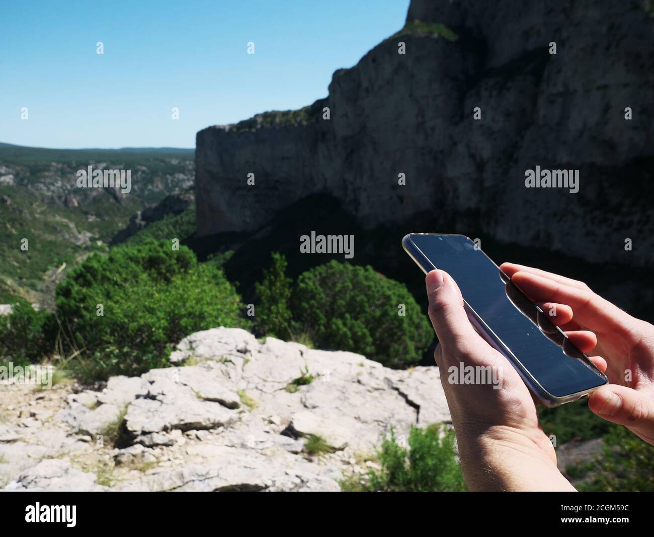 Foto de mano de un excursionista mirando su teléfono mientras senderismo en el desierto con la cima de las montañas en el fondo Foto de stock