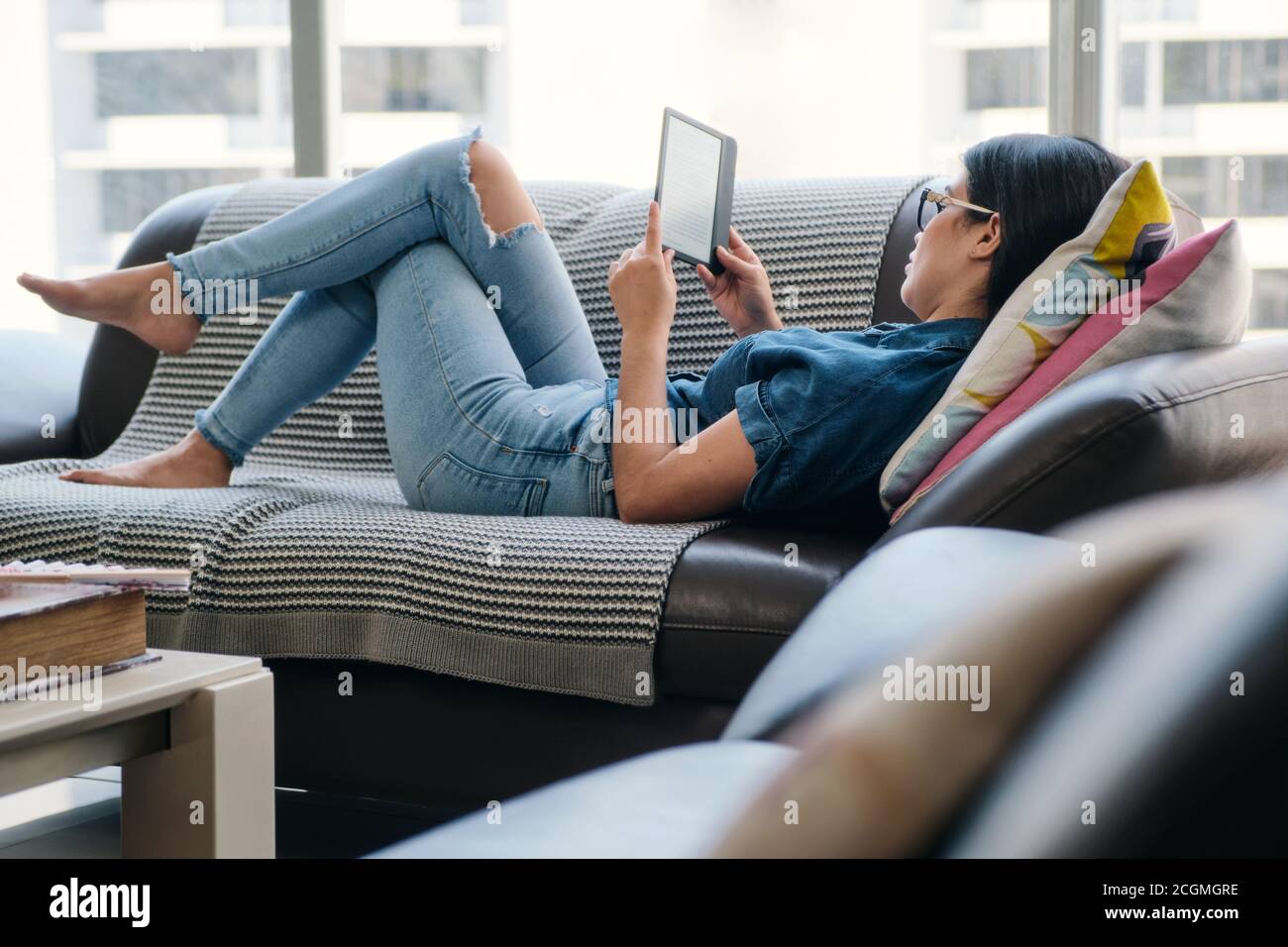 Mujer joven sosteniendo eReader y leyendo Ebook Foto de stock