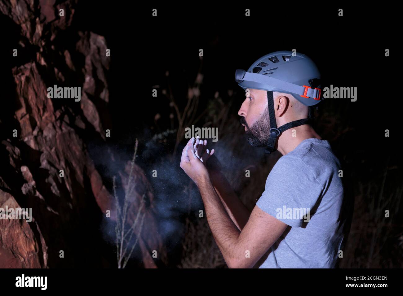 El escalador masculino hispano sopla tiza de sus manos Foto de stock