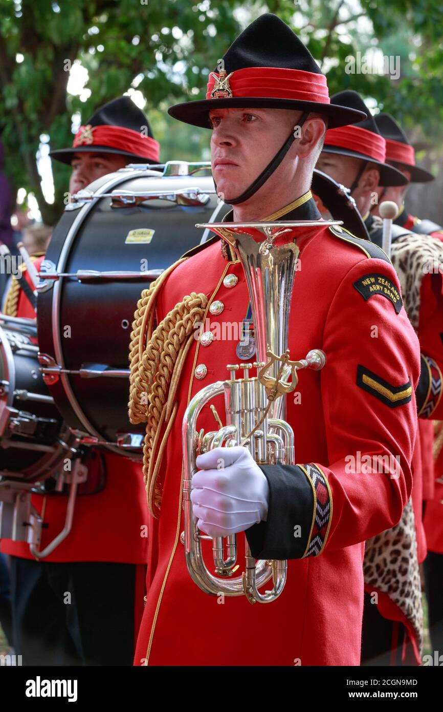 Un músico de la banda del Ejército de Nueva Zelanda. Lleva un uniforme ceremonial rojo con un sombrero negro de 'exprimidor de limón' y lleva un cuerno de barítono Foto de stock