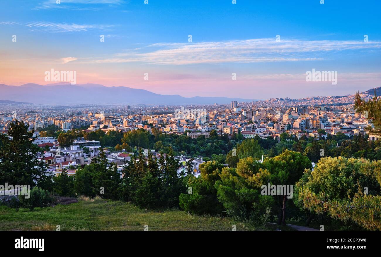 Vista de Atenas y sus zonas residenciales desde la cima de la colina de Pnyx en la suave luz del sol de la noche con gran cielo de la puesta de sol Foto de stock