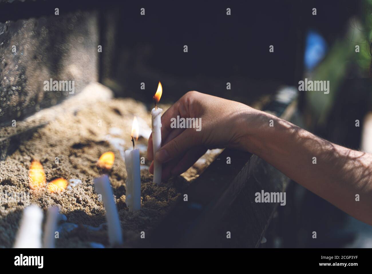 Mujer orando y quemando velas en el jardín de la casa de la Virgen María. Quemando velas blancas en el soporte. Adoración Foto de stock