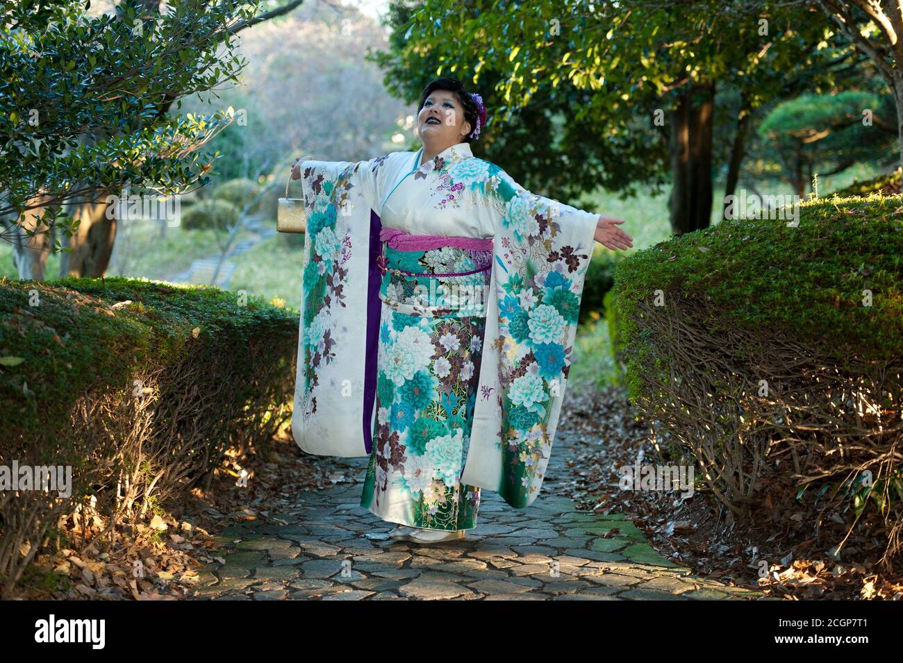 Hermoso adolescente japonés con kimono tradicional mirando con brazos estirados alabando, agradeciendo y celebrando la llegada del día de la Edad. Foto de stock
