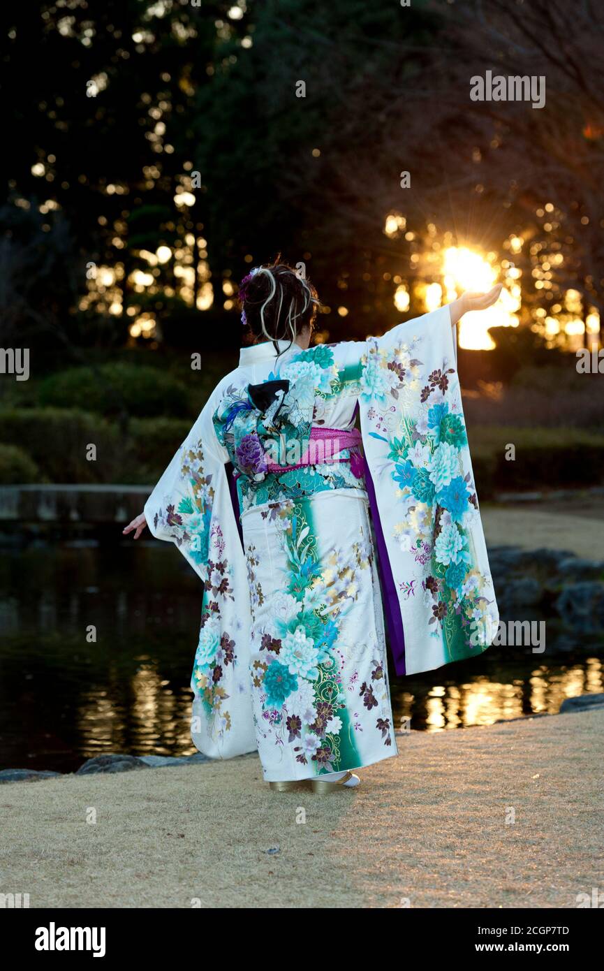 Adolescente japonés con kimono tradicional espalda y los brazos extendidos con el hermoso sol y la llamarada celebración de la llegada del día de la Edad. Foto de stock