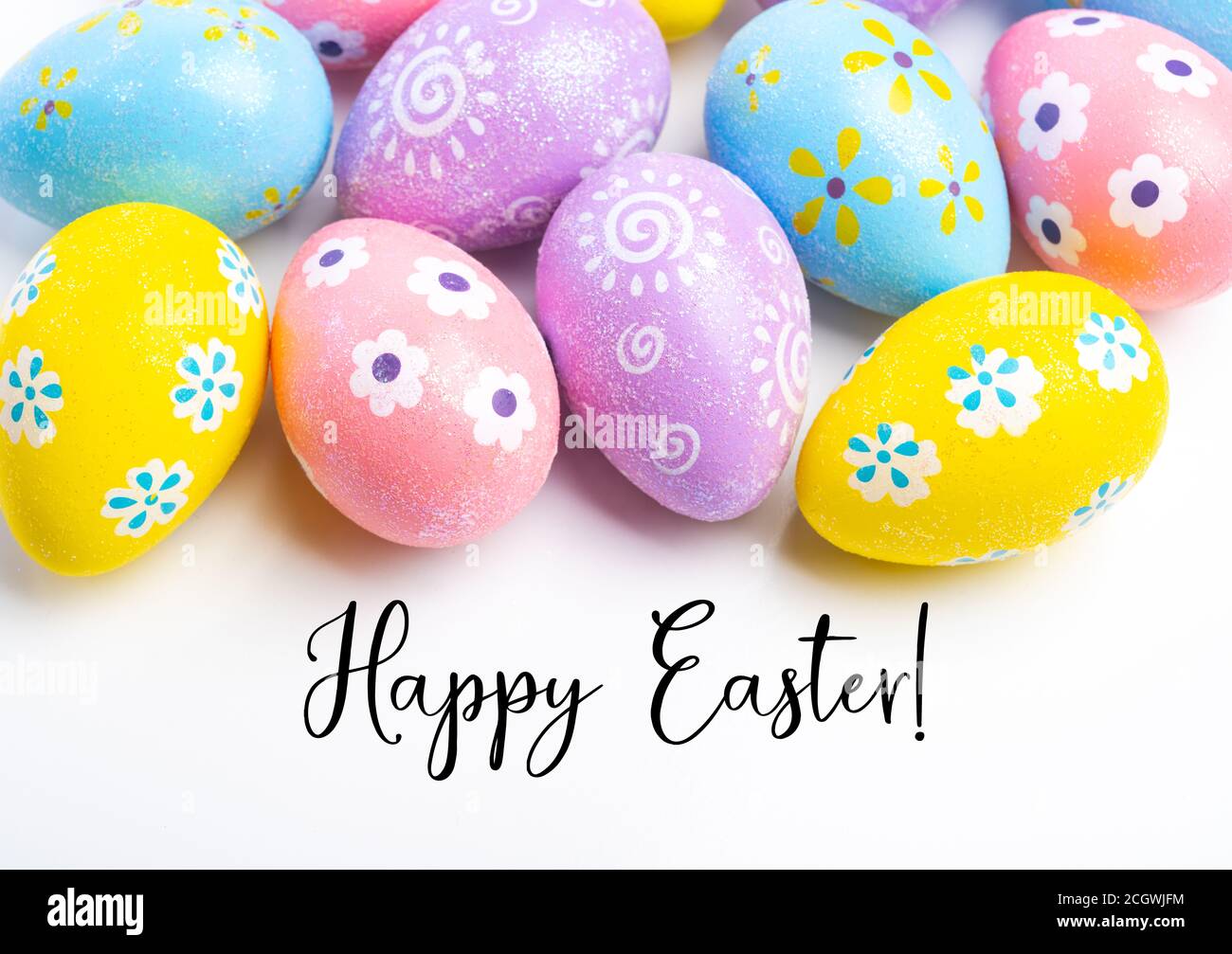 Coloridos huevos de Pascua sobre fondo blanco con saludo Foto de stock