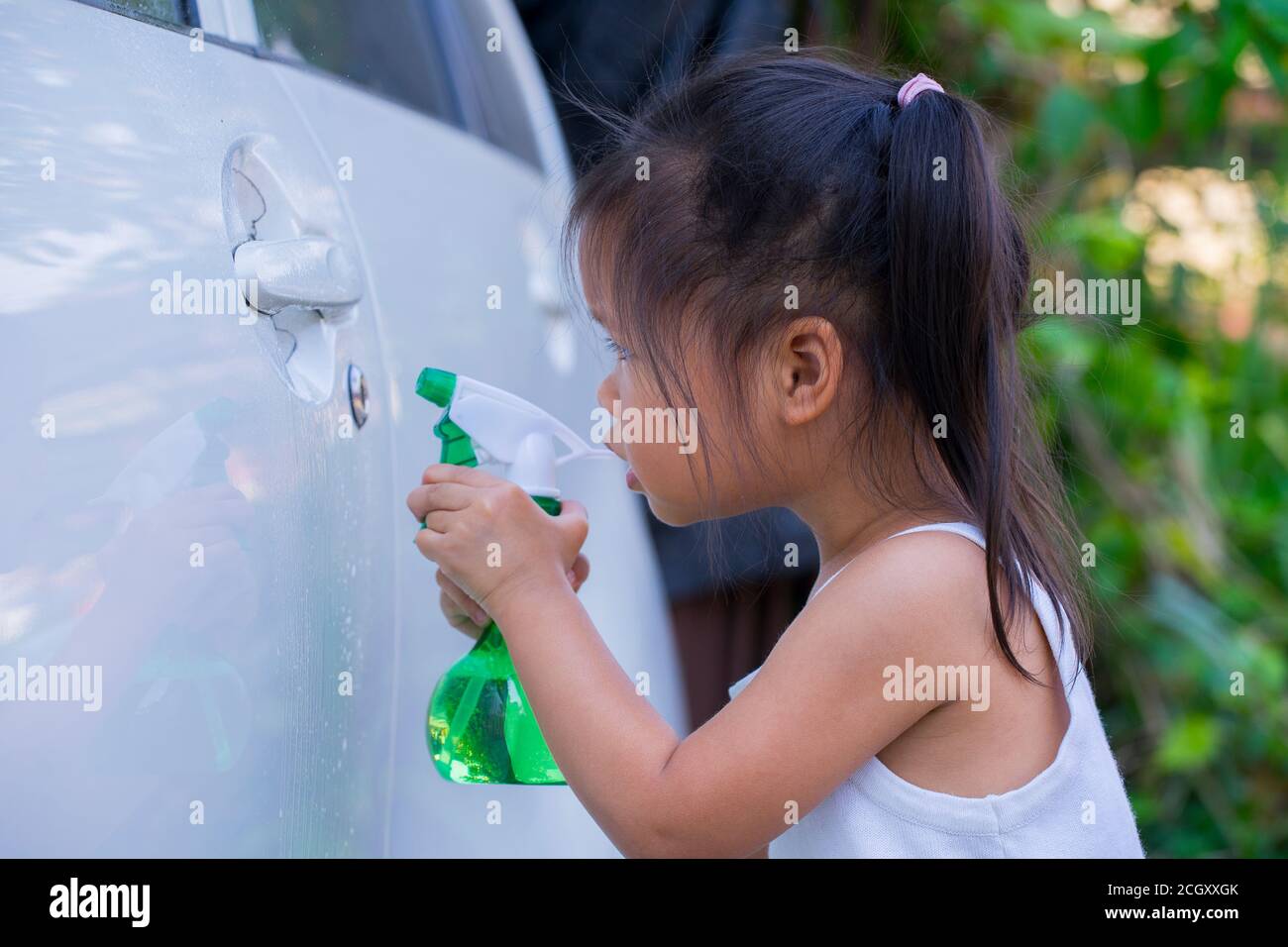 Los niños asiáticos restaban el jabón para limpiar el tirador de la puerta del coche. Foto de stock