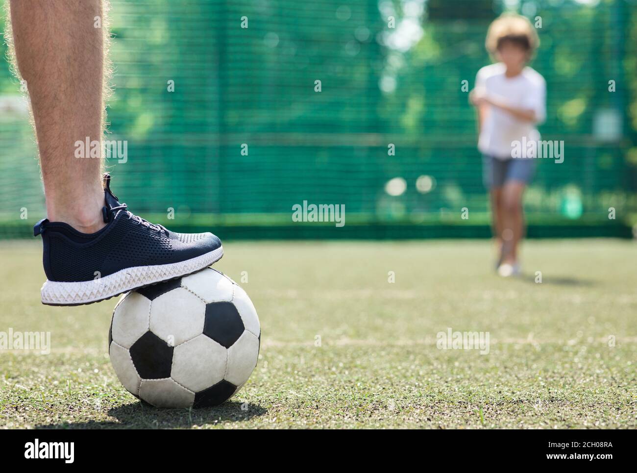 Jugador pisando el balón de fútbol de pie en el campo verde Foto de stock