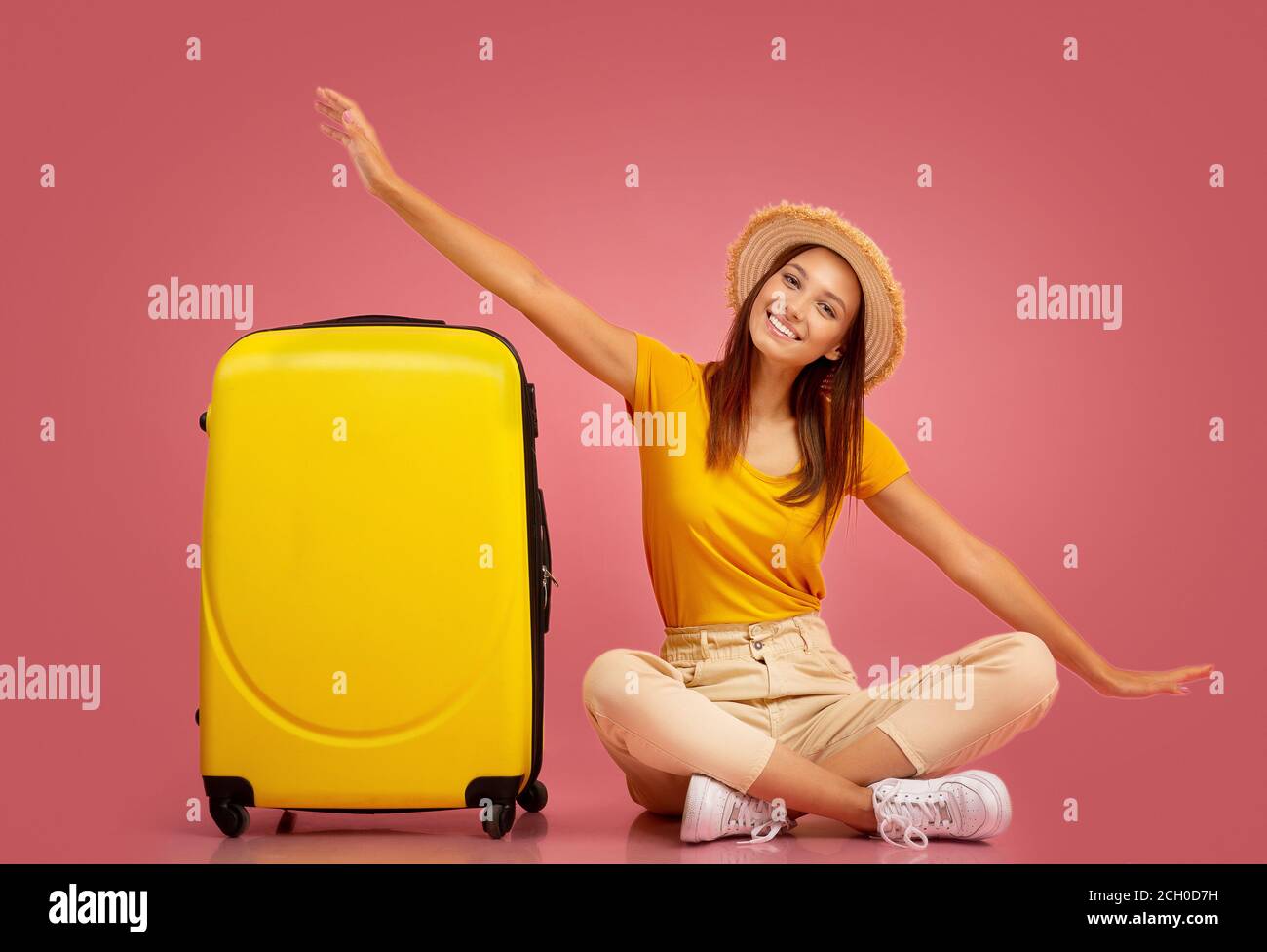 Chica emocionada sentada por maleta, imitando el avión Foto de stock