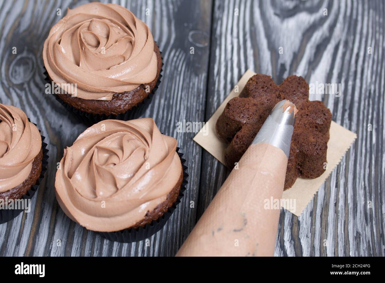 Cupcakes de chocolate con crema de queso crema. Junto a ella hay una bolsa  de pastelería con crema para la decoración Fotografía de stock - Alamy