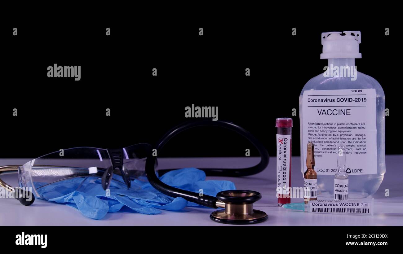 Vacuna para el concepto de pandemia de coronavirus. COVID-19 atributos: Análisis de sangre, vacuna, inyección, gafas protectoras y guantes azules. Foto de stock