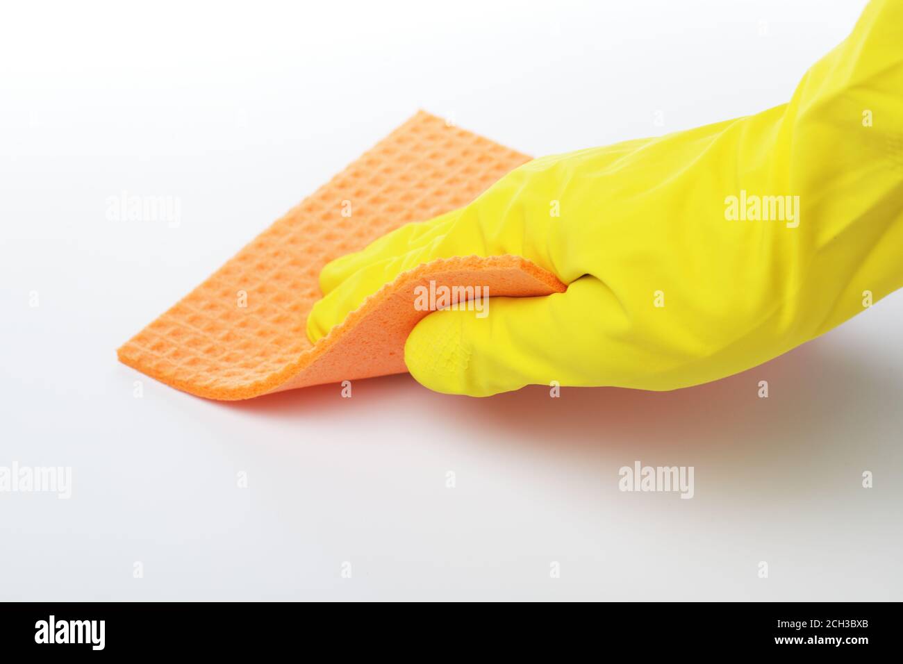 Mano en guante de goma con una esponja de celulosa contra blanco Foto de stock