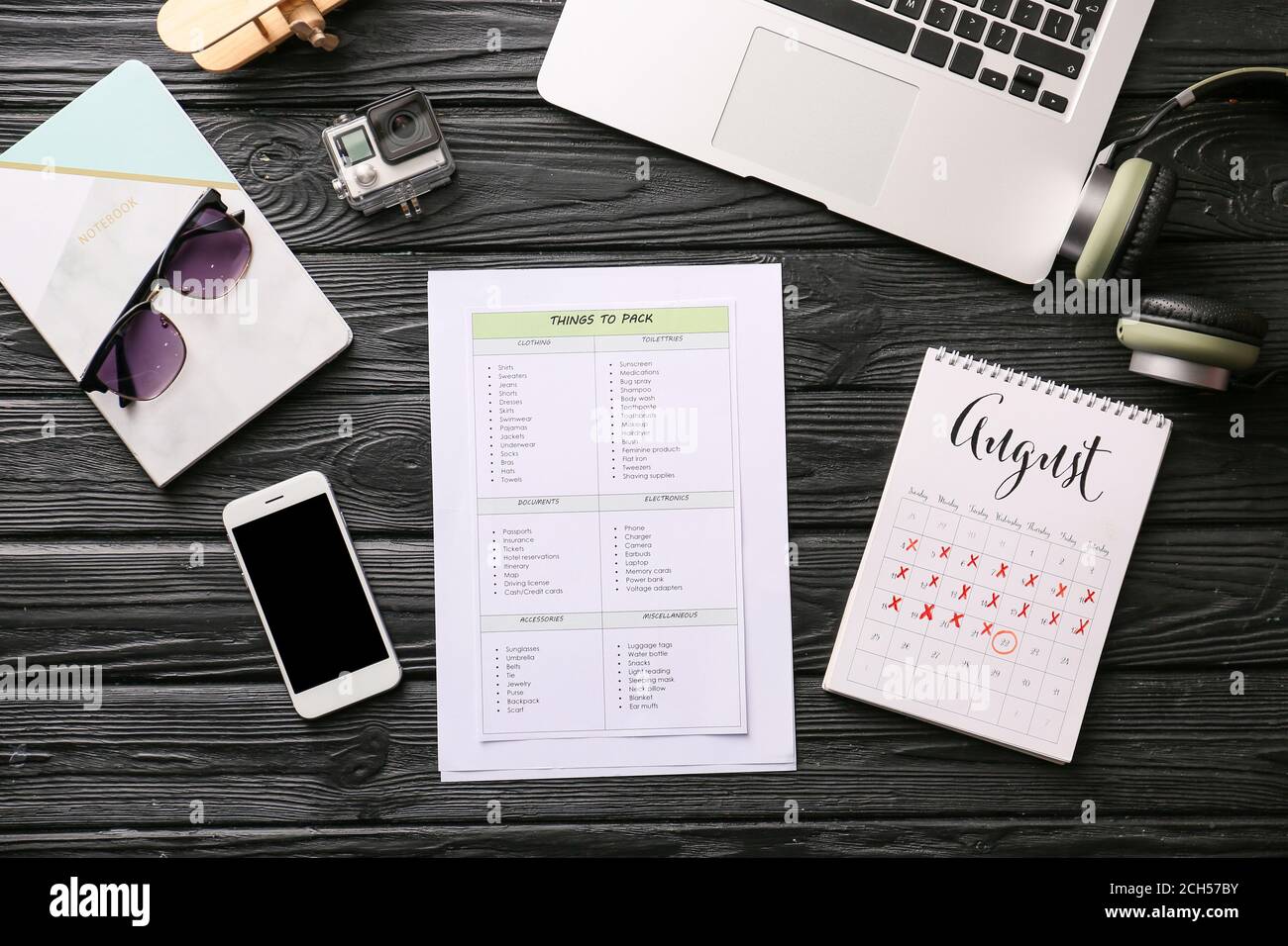 Consulta la lista de cosas para empacar para viajar con calendario,  portátil y teléfono móvil sobre fondo de madera Fotografía de stock - Alamy