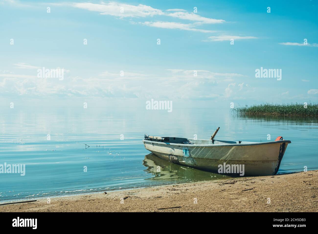 El hermoso paisaje de un barco blanco de madera simple en el gran lago azul. Concepto de vacaciones en el lago. Buen día de verano en la naturaleza. Foto de stock
