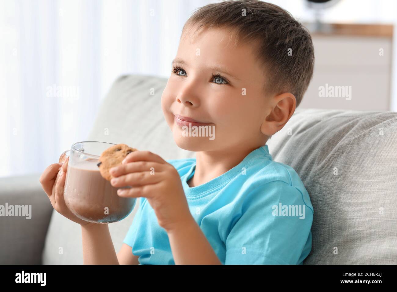 Niño que bebe leche de chocolate y que come galletas en casa Fotografía de  stock - Alamy