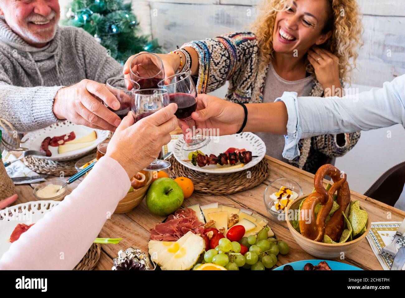 Los amigos de la familia se divierten juntos en el invierno comiendo la comida encendido una mesa de madera - concepto de amistad y gente caucásica disfrutar de la celebración en casa o. Foto de stock