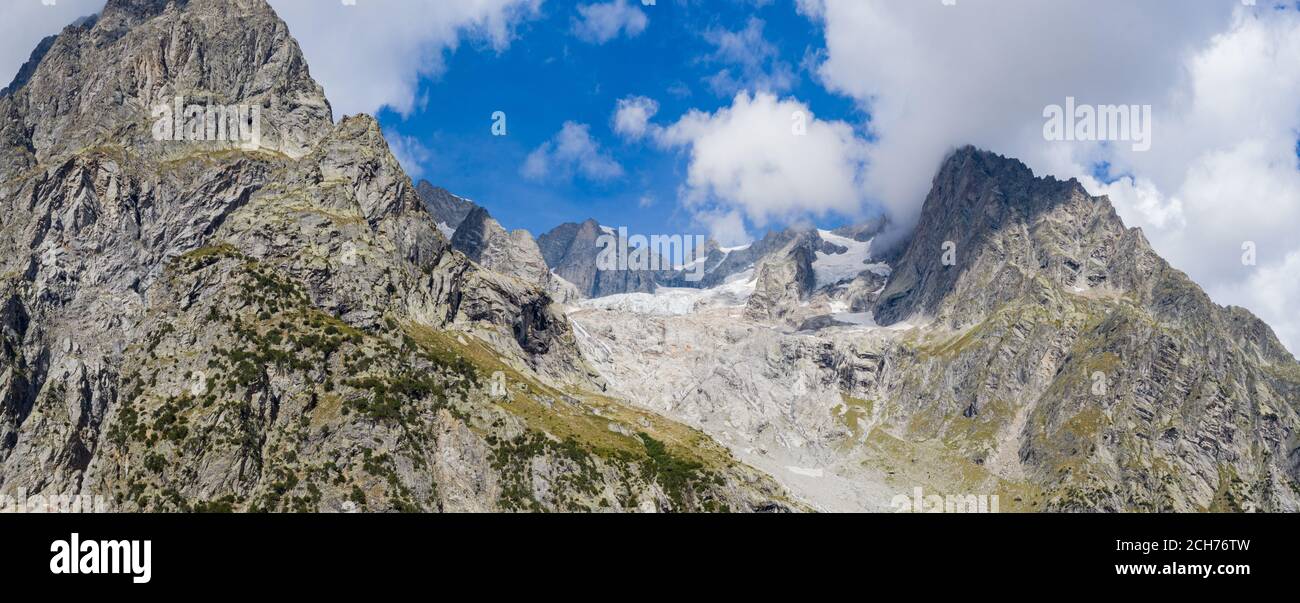 Panorama de un valle de montaña alpina y picos. Altos picos de montaña y un glaciar y cascadas en el lado italiano del Mont Blanc masiva. Foto de stock