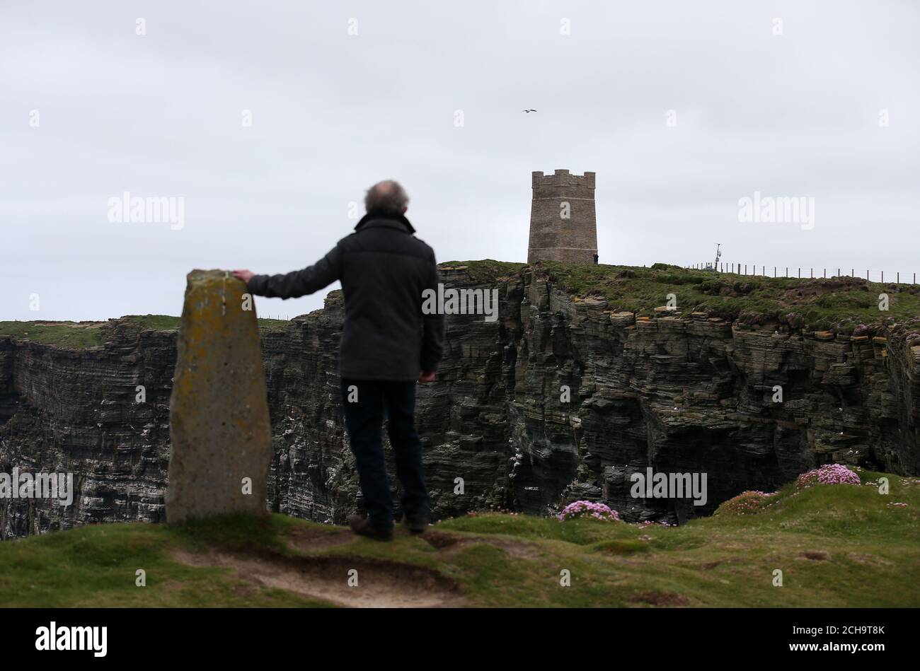 Los visitantes caminan a lo largo de las cimas del acantilado sobre el mar en Marwick Head en Orkney, donde se alza la torre construida para honrar la memoria de Lord Kitchener. Foto de stock