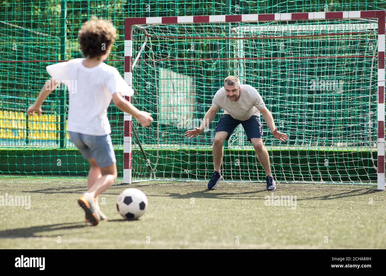 Niño jugando al fútbol, pateando el balón al gol Foto de stock