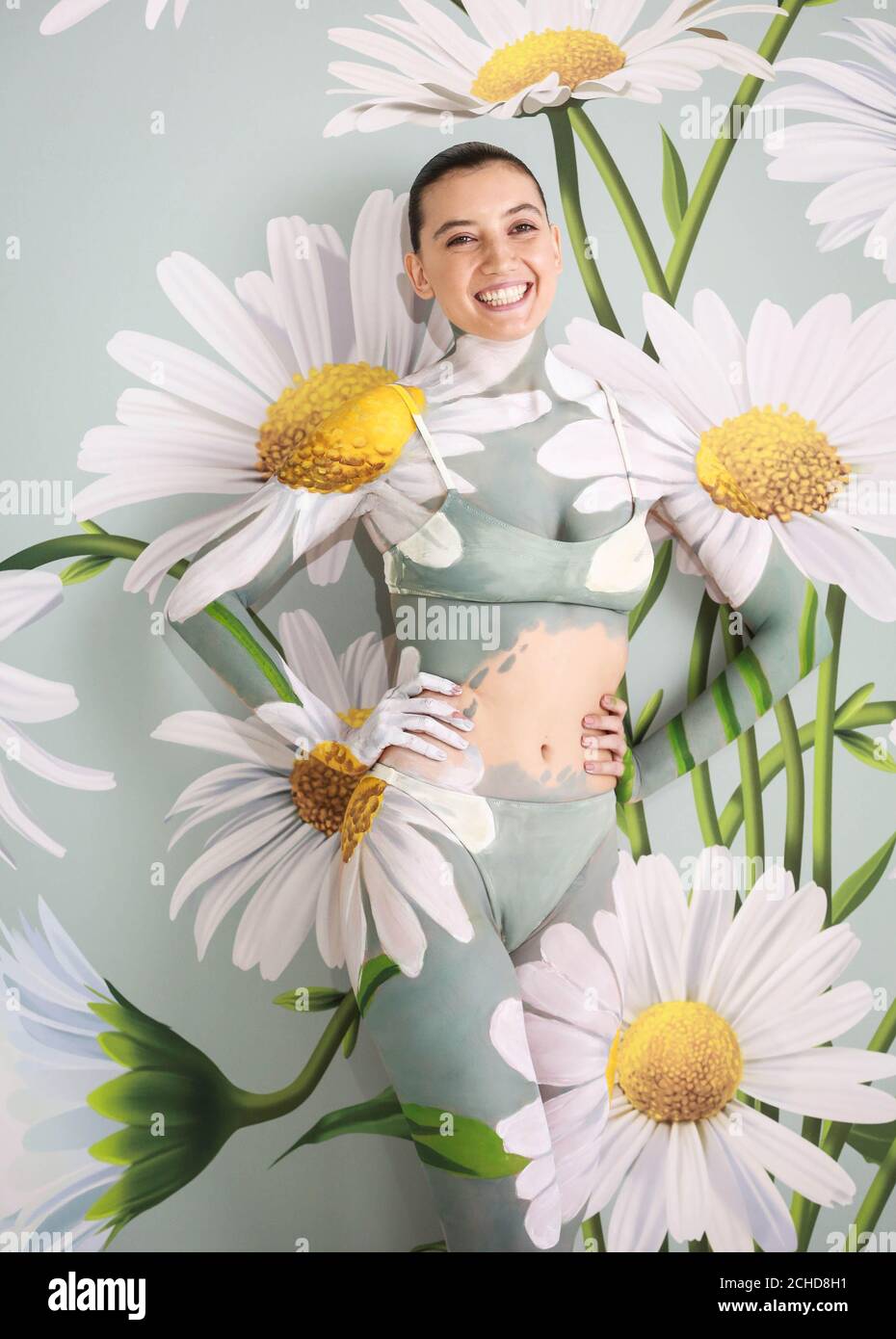 Daisy Lowe ha sido camuflado en una pared de margaritas por la artista líder mundial de pintura corporal Carolyn Roper, para mostrar la función de modo ambiental del televisor Samsung QLED. El Foto de stock