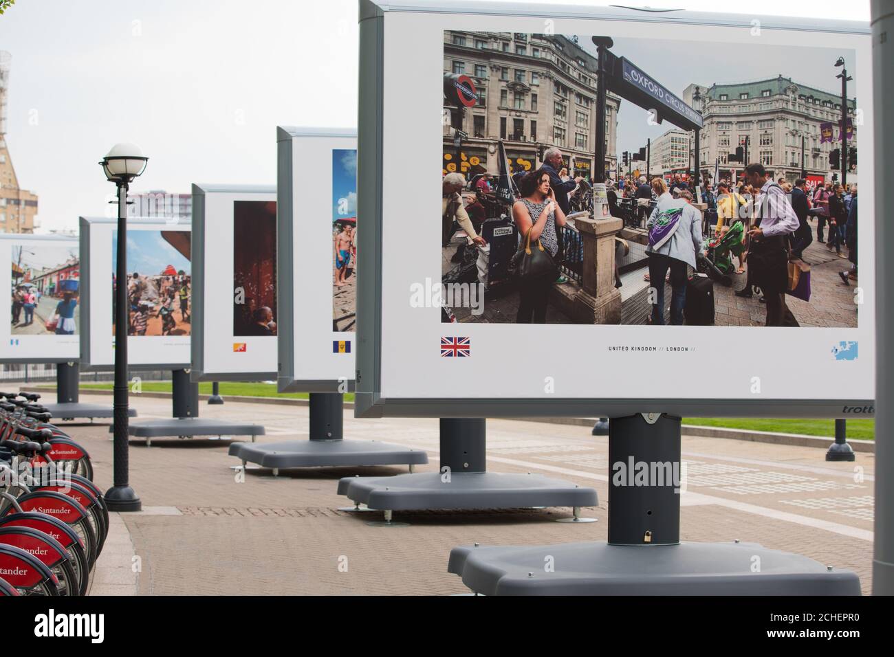 Miembros del público miran imágenes de capitales de todo el mundo por el fotógrafo Jeroen Swolfs en el debut británico de la exposición de fotografía Streets of the World en Canary Wharf, Londres. Foto de stock
