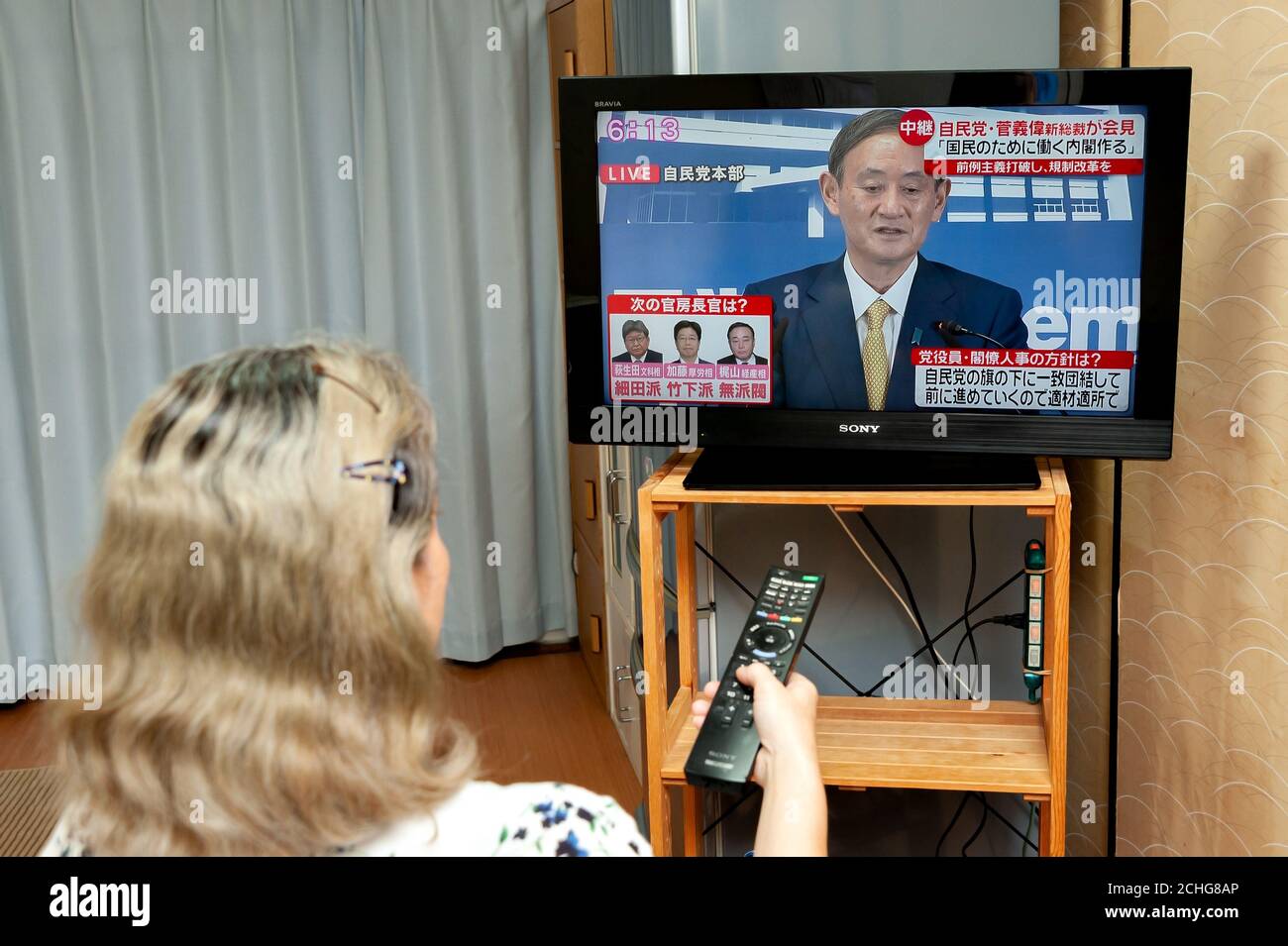 Mujer ve la conferencia de prensa transmitida en vivo por la televisión japonesa por Yoshihihihihide Suga, el nuevo líder del Partido Liberal Democrático (PDL). Foto de stock