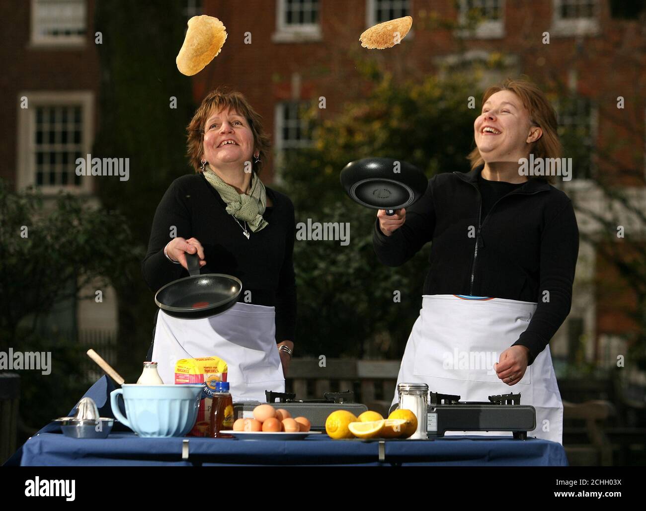 Las consultoras de alimentos Helen Woods (izquierda) y Maureen Porteous demuestran sus habilidades de pancake volteando en Soho Square, Londres antes del martes de Shrove, el 5 de febrero. Foto de stock