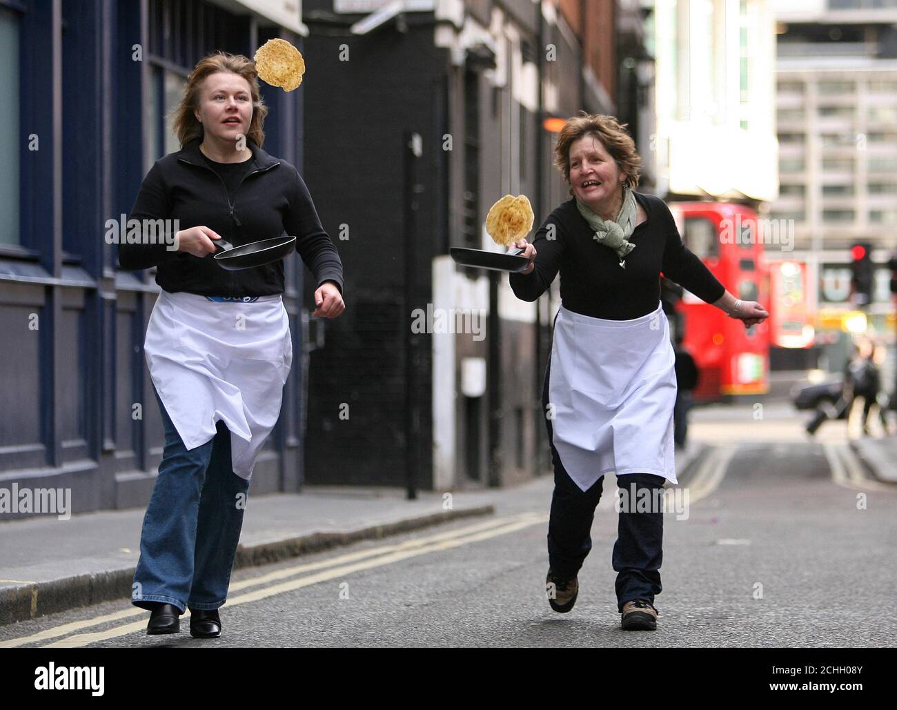 Las consultoras de alimentos Helen Woods (derecha) y Maureen Porteous demuestran sus habilidades de pancake volteando en Soho Square, Londres antes del martes de Shrove, el 5 de febrero. Foto de stock
