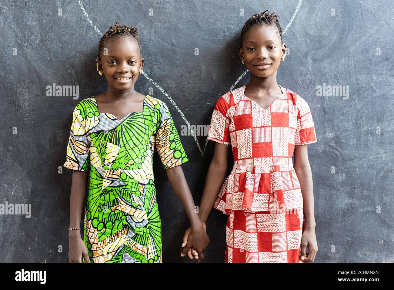 Pareja de niños africanos posando adentro en la explotación del edificio de la escuela Manos Foto de stock