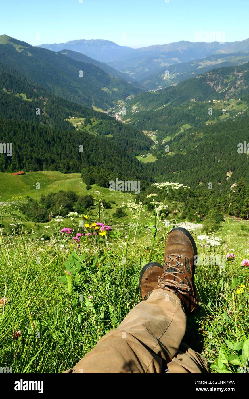 Relájese en los Alpes italianos. Imagen de piernas tumbadas y un valle verde en los Alpes. Foto de stock