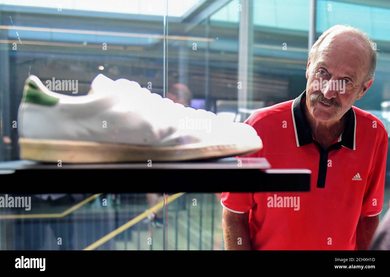 El ex tenista Stan Smith mira sus zapatillas mientras asiste a las  celebraciones del 70 aniversario del fabricante alemán de ropa deportiva  Adidas en la exposición de historia de la compañía en