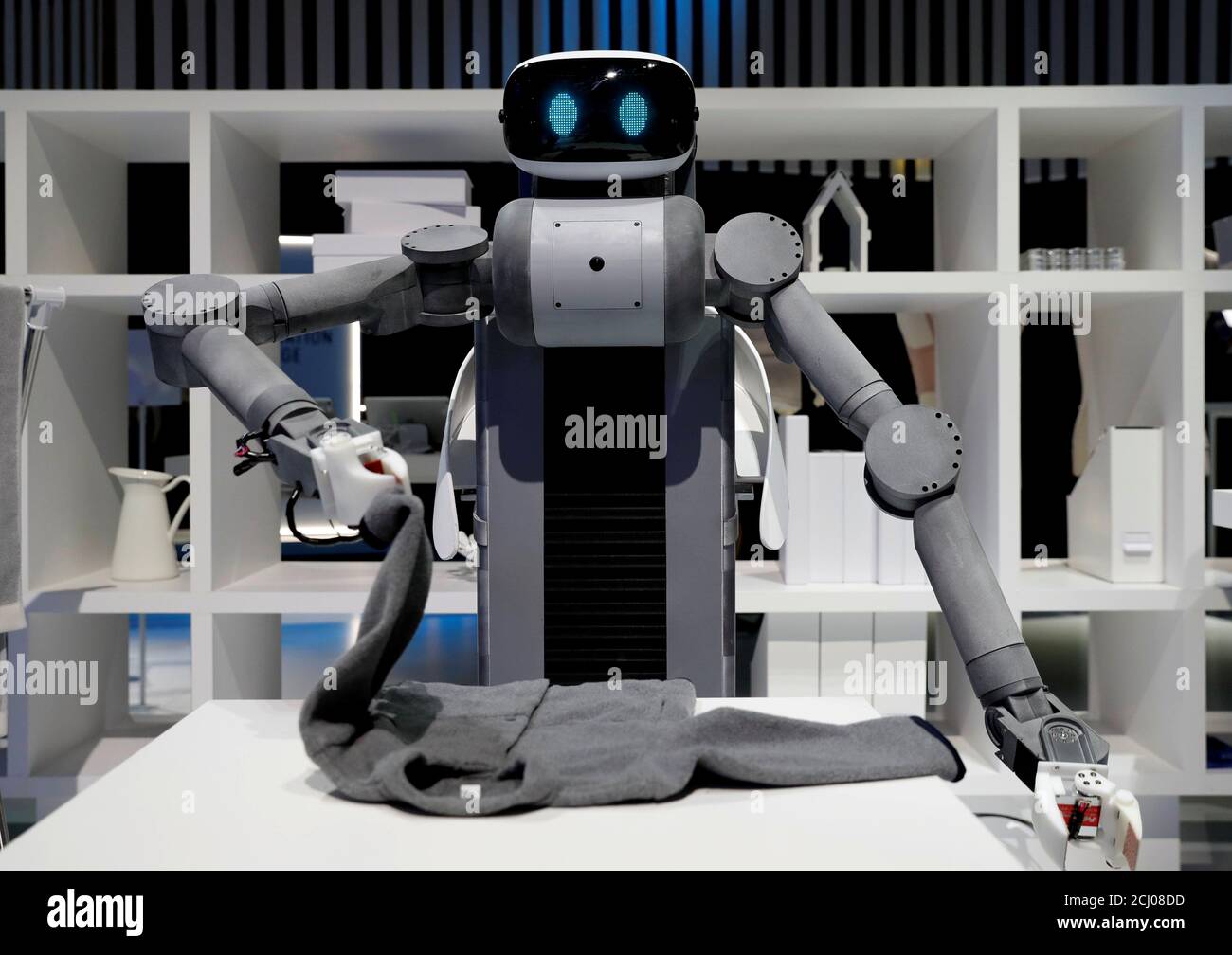 El robot Ugo, controlado a distancia, dobla una ropa durante su exposición  en el salón de innovación de Japón de la sede de la cumbre de líderes del  G20 en Osaka, Japón,