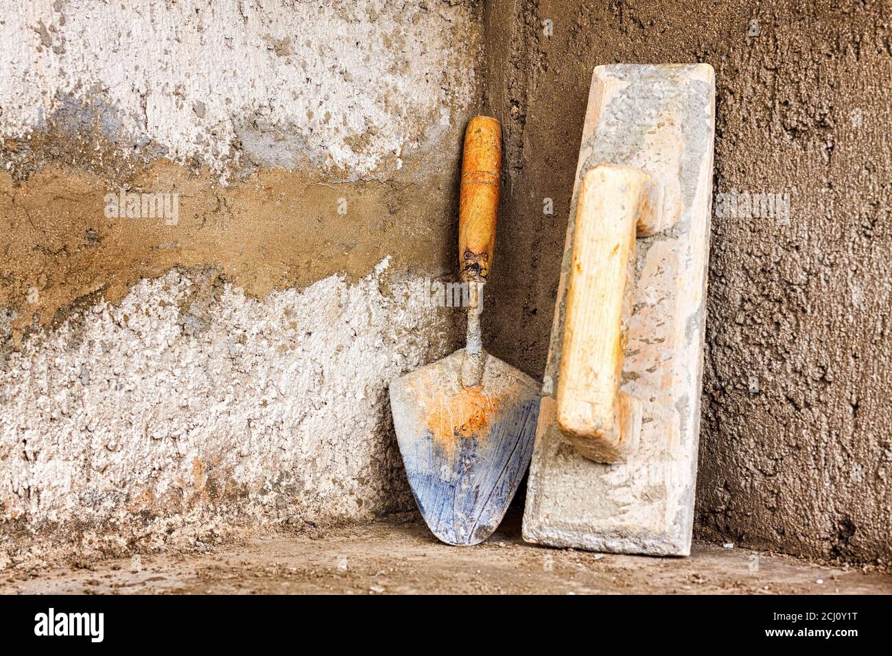 Herramientas de albañilería inclinadas sobre una pared de concreto rugoso  Fotografía de stock - Alamy