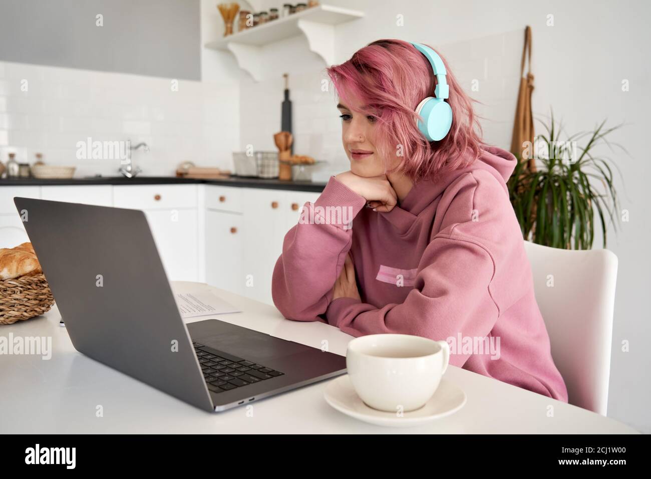 Joven mujer hipster con pelo rosa usando auriculares en casa. Foto de stock