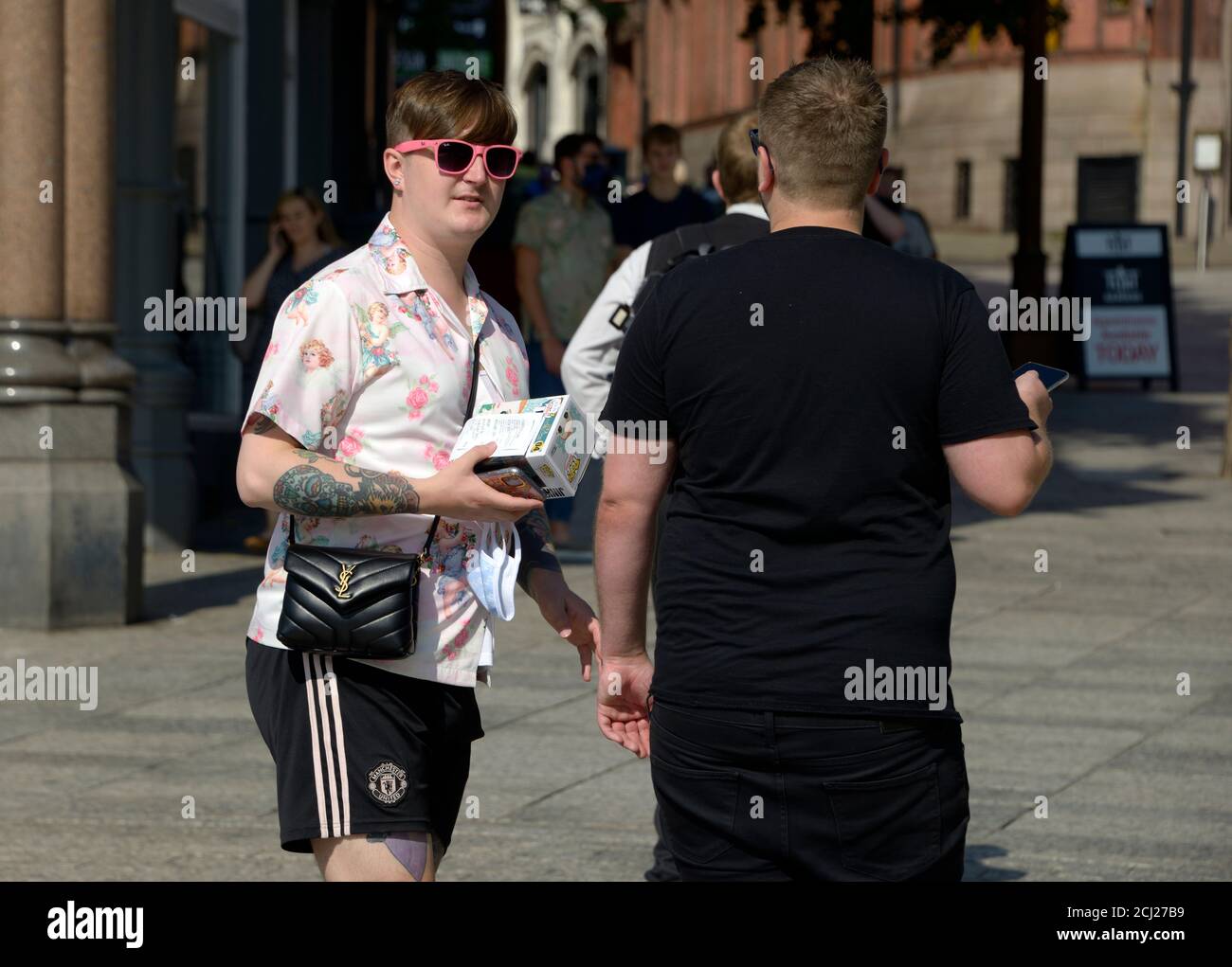 Chicos gays, en conversación. Bolso de mano y gafas de sol de color rosa  Fotografía de stock - Alamy