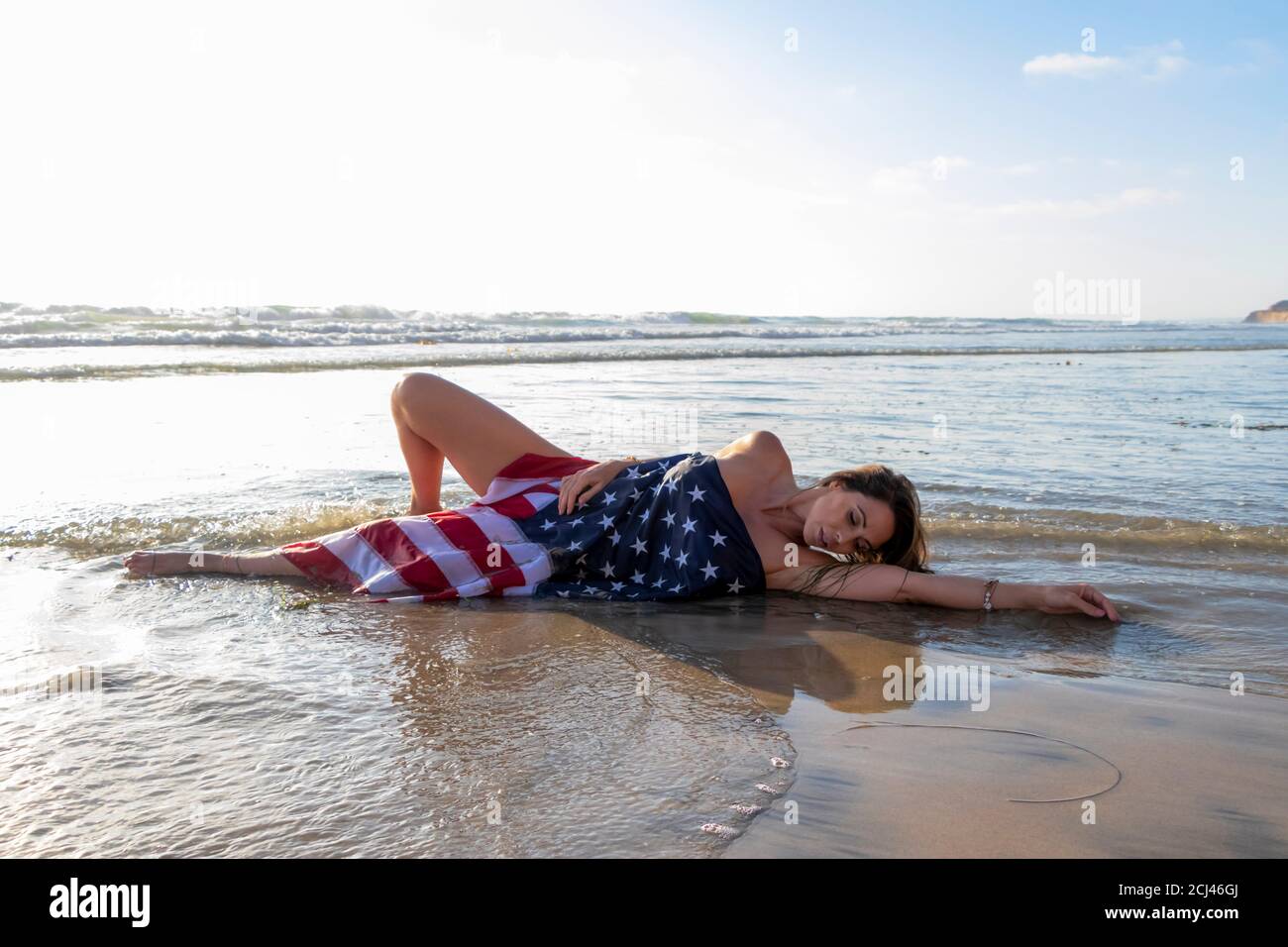 Una hermosa morena modelo plantea desnuda con una bandera americana En la  playa Fotografía de stock - Alamy