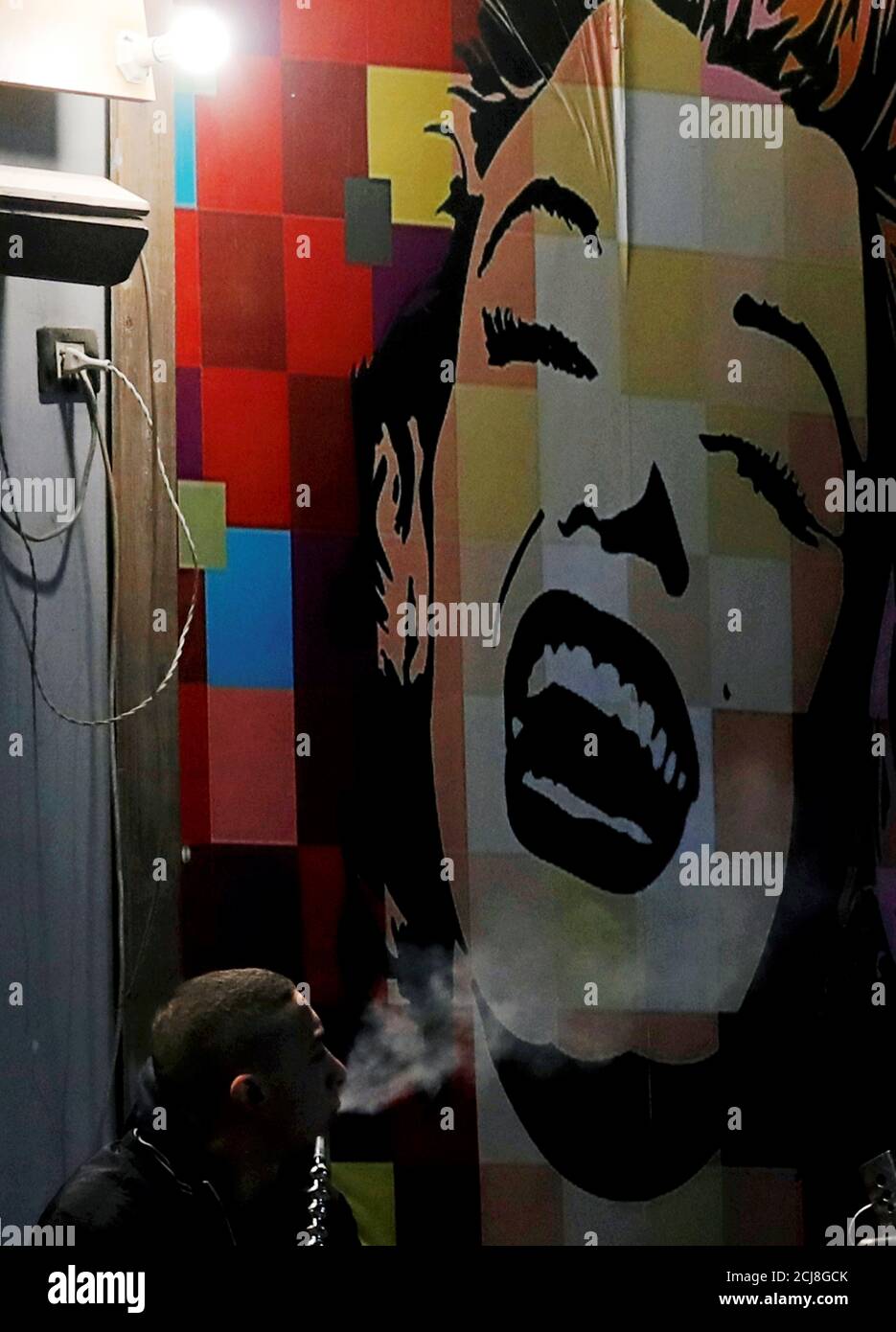 Un hombre fuma shisha cerca de una imagen de Marilyn Monroe en el Fishawi Cafe en el Cairo, Egipto 23 de diciembre de 2018. REUTERS/Amr Abdallah Dalsh Foto de stock
