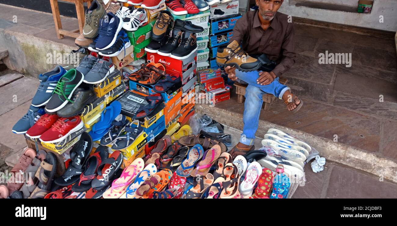 DISTRITO DE KATNI, INDIA - 22 DE SEPTIEMBRE de 2019: Un hombre de ventas  asiático mostrando cosas de calzado en la tienda de moda en la ciudad local  calle mercado lugar Fotografía