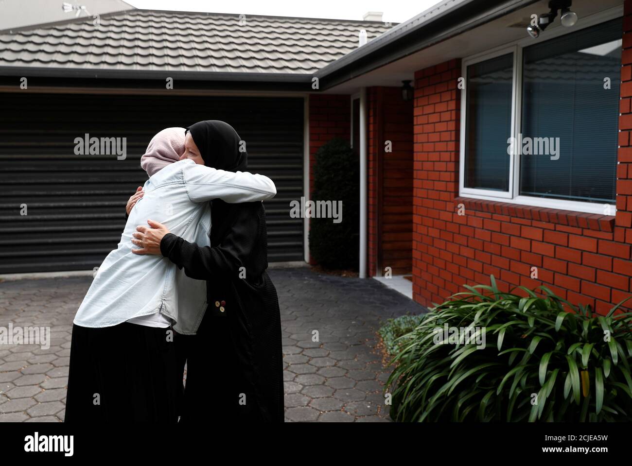 Zahra Fathy, viuda de Hussein Moustafa, de 70 años, un inmigrante egipcio que perdió la vida en los tiroteos de Christchurch, abraza a un vecino que vino a comprobar cómo estaba haciendo frente Zahra, fuera de su casa en Christchurch, Nueva Zelanda 30 de marzo de 2019. "Es difícil seguir pensando en lo que pasó, así que tengo que escapar de esto y pensar en lo que es siguiente", dijo Fathy. Su marido había pasado tiempo en la mezquita la mayoría de los días, organizando su biblioteca de textos religiosos y atendiendo a un huerto, que proporcionaba a la comunidad calabazas, cohetes y brócoli. REUTERS/Edgar su BUSCAR 'SHOOTING su Foto de stock