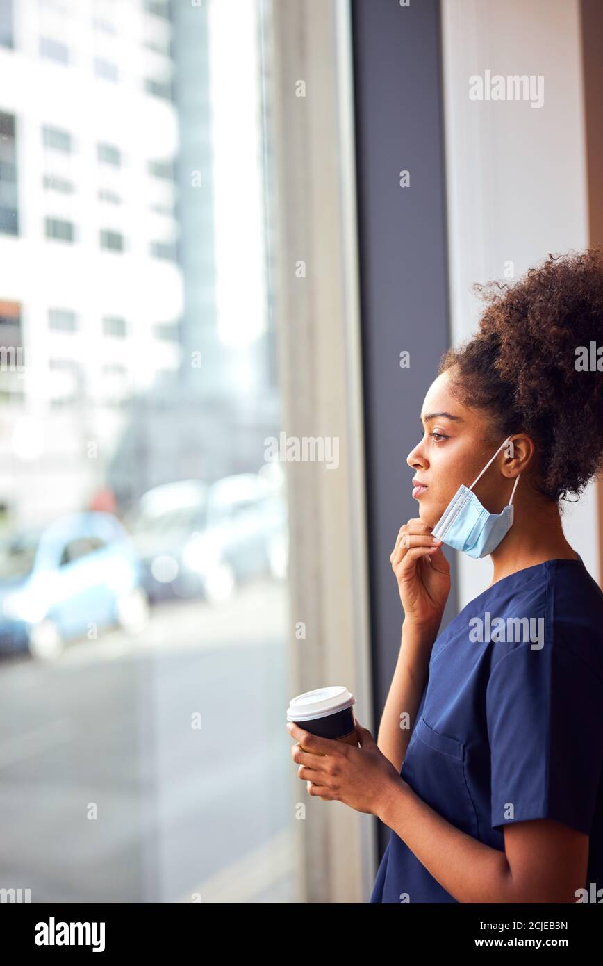 Enfermera sobrecorda en Scrubs con máscara facial toma descanso de café