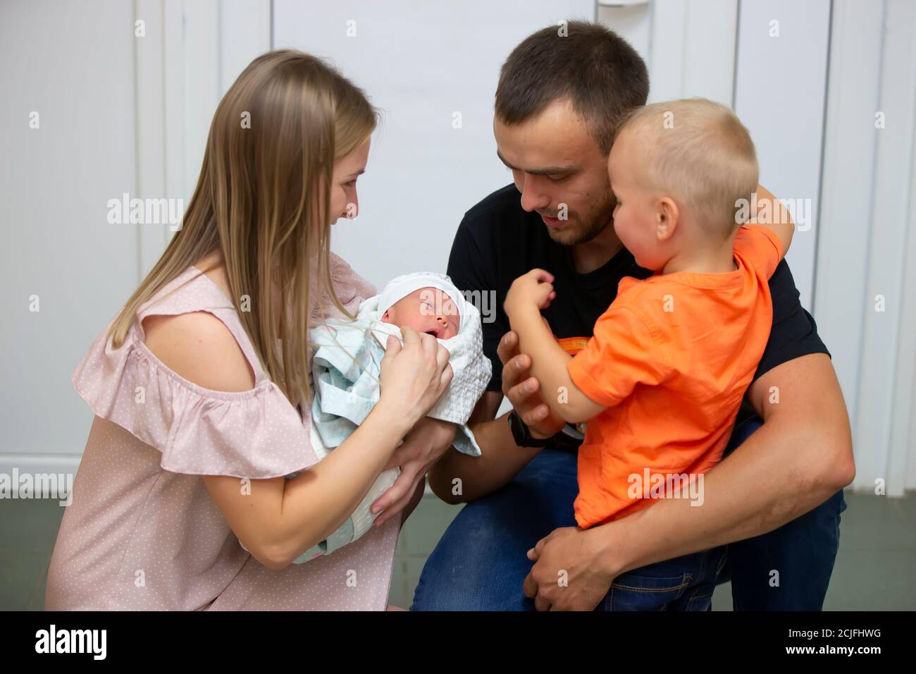 Familia Con Un Bebe Recien Nacido Mama Papa Y Su Hijo Miran A La Hermana Recien Nacida Fotografia De Stock Alamy
