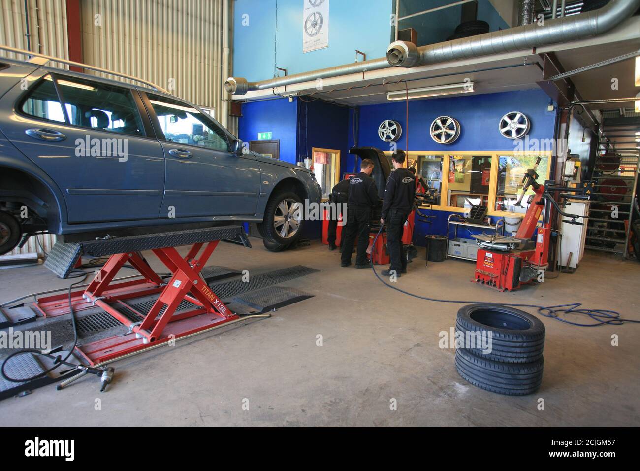 TALLER DE NEUMÁTICOS con el coche en el ascensor que tendrá para cambiar  los neumáticos Fotografía de stock - Alamy