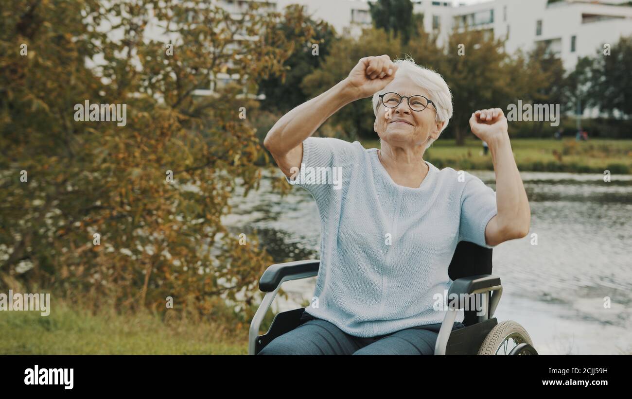 Feliz anciana, abuela, bailando con las manos en la silla de ruedas cerca  del río. Foto de alta calidad Fotografía de stock - Alamy