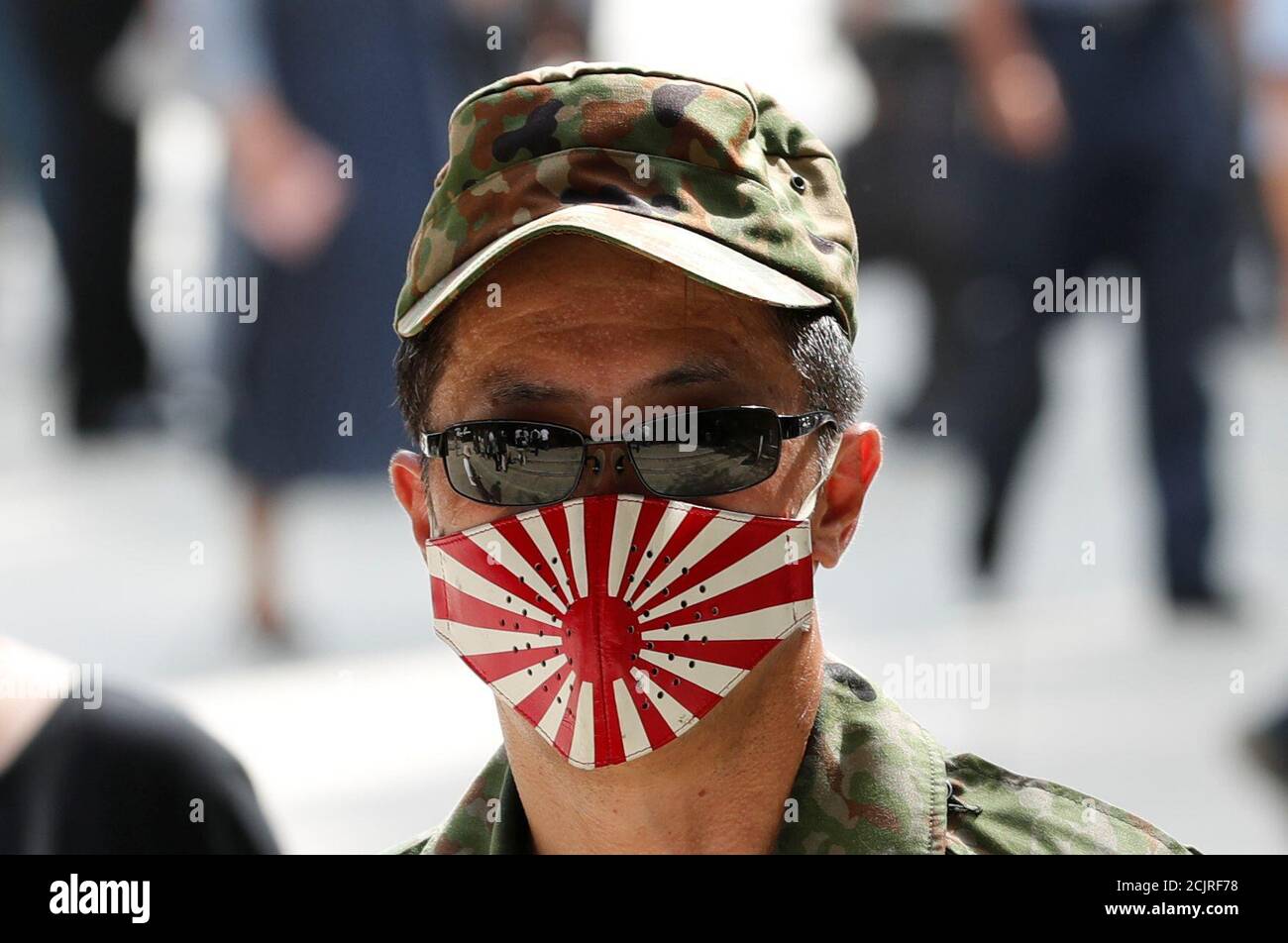 Un hombre lleva una máscara con bandera militar imperial japonesa en el  Santuario Yasukuni en Tokio, Japón 15 de agosto de 2019, en el 74º  aniversario de la rendición de Japón en